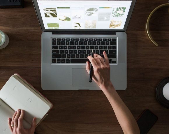 Una persona trabajando con el ordenador y un cuaderno